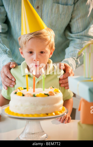 Un giovane bambino che spegne le candeline sulla torta del compleanno Foto Stock