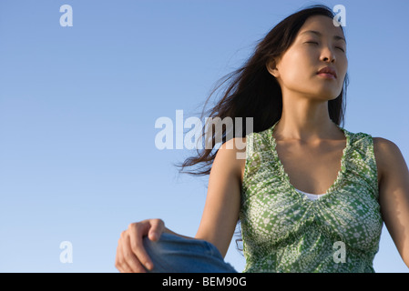 Donna seduta all aperto con gli occhi chiusi Foto Stock