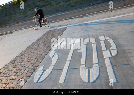 STOP' la segnaletica stradale in corrispondenza di una intersezione, un " commuter " in sella ad una bicicletta in background. Mountain View, California, Stati Uniti d'America Foto Stock