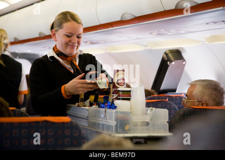 Equipaggio di cabina / hostess aria serve drinks e spuntini per i passeggeri di un carrello della spesa durante un volo Easyjet Foto Stock