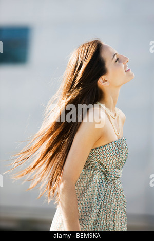 Giovane donna passeggiate all'aperto, capelli lunghi tousled dal vento Foto Stock