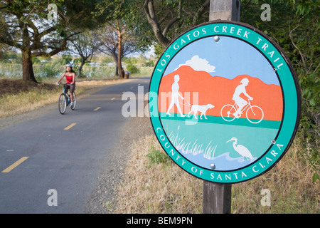 Segno di Los Gatos Creek Trail, multi-uso trail, nella contea di Santa Clara. Una femmina di ciclista in background. Foto Stock