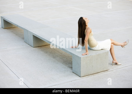 Giovane donna rilassante sul banco in City Square, ad alto angolo di visione Foto Stock