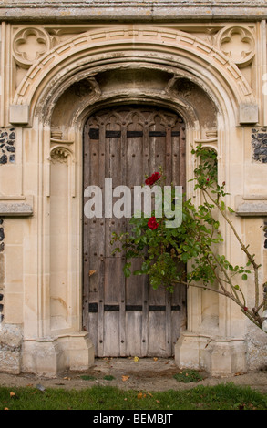 Molto di una vecchia porta di legno in ornato portale della chiesa di San Pietro e di San Paolo in Cavendish, Suffolk, Inghilterra. Foto Stock