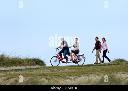 Scuotipaglia e un paio di equitazione biciclette tandem nelle dune lungo la costa del Mare del Nord Foto Stock