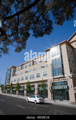 Un inclinato in vista di un edificio con appartamenti e uffici, visto da una divisa road. Park Broadway su El Camino Real, Millbrae Foto Stock