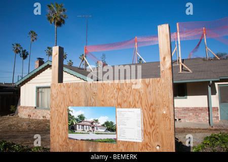 Un cartello che mostra i dettagli di un nuovo singolo casa famiglia progetto di costruzione con la vecchia casa in background. California Foto Stock