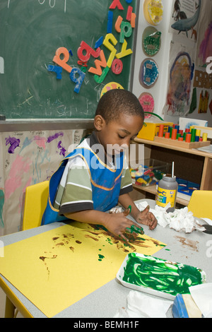 Afro-americano di ragazzo di età prescolare dito pittura in aula Foto Stock