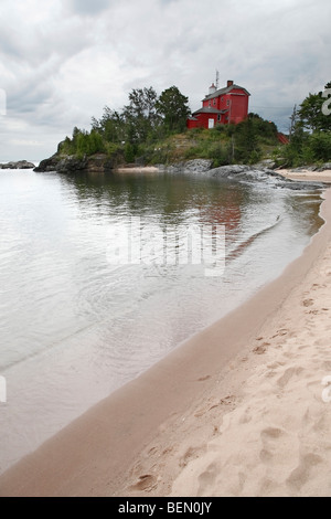 Faro rosso sul lago Superior nel Michigan, USA nuvole ovattano la spiaggia sabbiosa, nessuno ha un angolo basso dall'alto del paesaggio nuvoloso sopra l'orizzonte ad alta risoluzione Foto Stock