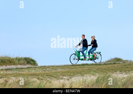 Paio di equitazione biciclette tandem nelle dune lungo la costa del Mare del Nord Foto Stock