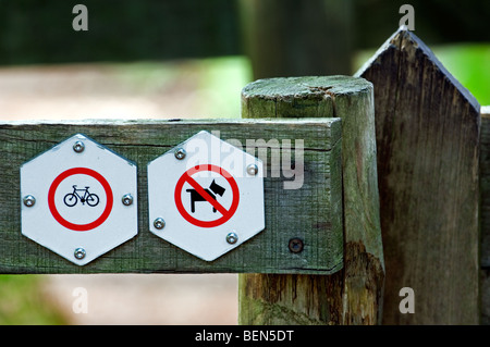 Cartelli di divieto sulla staccionata in legno all ingresso della riserva naturale di vietare l'accesso ai cani e biciclette Foto Stock