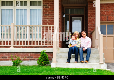 Famiglia giovane seduto sulla parte anteriore passi di casa Foto Stock