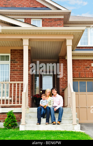 Famiglia giovane seduto sulla parte anteriore passi di casa Foto Stock