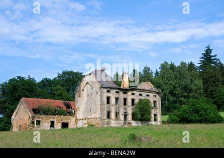 Abbandonata e fatiscente casa colonica e fienile in corrispondenza di un bordo di una foresta, un paradiso per la fauna selvatica a causa di spopolamento rurale Foto Stock