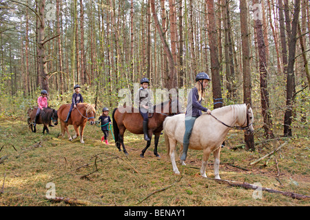 Bambini equitazione sulla loro pony attraverso una foresta Foto Stock