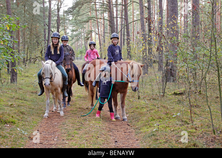 Bambini equitazione sulla loro pony attraverso una foresta Foto Stock