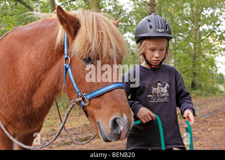 Ritratto di una giovane ragazza in piedi accanto al suo pony cercando in questione Foto Stock