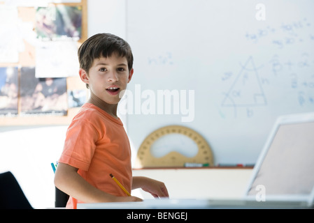 Scuola elementare studente in aula, guardando sopra la spalla Foto Stock