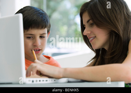 Little Boy guarda la sorella utilizzare il computer portatile Foto Stock