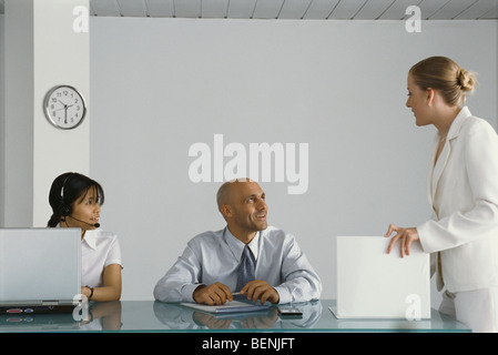 I giovani dirigenti di sesso femminile in piedi da colleghi' desk, conversando Foto Stock