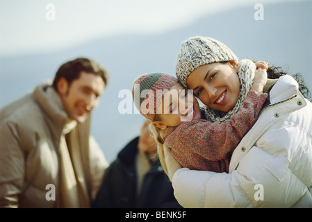 Bambina abbracciando la madre, famiglia in background Foto Stock