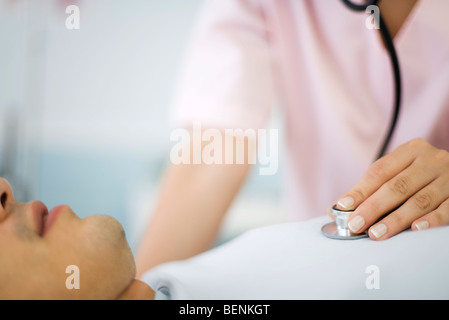 L'infermiera ascoltando il cuore del paziente utilizzando uno stetoscopio ritagliato Foto Stock