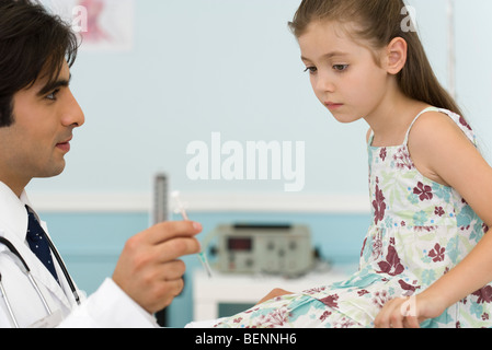 Pediatra spiegando la siringa per bambina Foto Stock