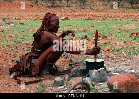 Donna Himba la cottura in casseruola sul fuoco aperto Kaokoland / Kaokoveld, Regione di Kunene, nel nord della Namibia, Sud Africa Foto Stock