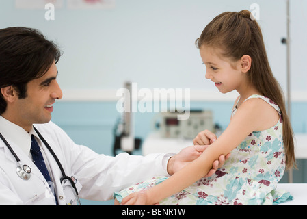 Gentile Dottore esaminando bambina del braccio Foto Stock