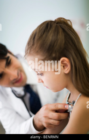 Pediatra ascoltando la bambina al torace con uno stetoscopio Foto Stock