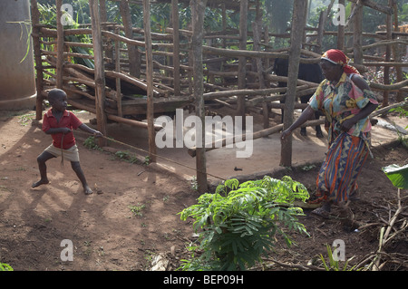 UGANDA madre e figlio tenendo lascia a compost pit Foto Stock