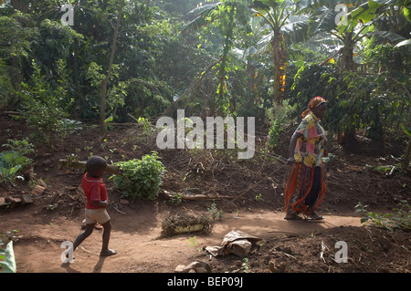 UGANDA madre e figlio tenendo lascia a compost pit Foto Stock