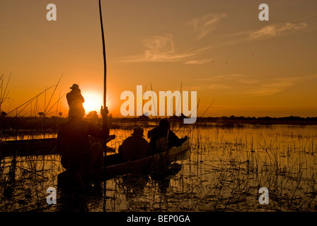 La gente a guardare il tramonto su una barca mokoro in Okavango Delta, Botswana, Africa. Foto Stock