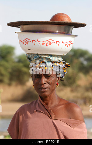 Close up ritratto di donna nera che trasportano merci nel piatto sul suo capo, Mali, Africa occidentale Foto Stock