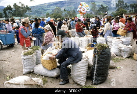 Uomo in tuta e hat seduta sul grande sacco di patate in altopiano locale Ecuador mercato. Foto Stock