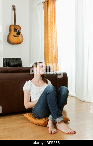 Giovane donna seduta sul pavimento Foto Stock