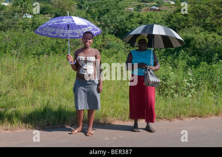 Due donne stesse ombreggiatura dal sole al di fuori di un villaggio vicino a Durban, Sud Africa Foto Stock