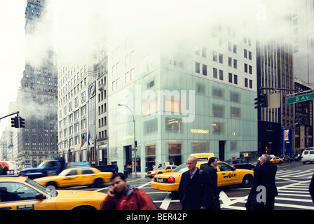 Vista invernale cercando la Quinta Avenue di New York City che dall'angolo di W 57th Street con acquirenti e taxi gialli e vapore. Foto Stock