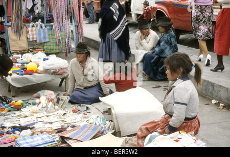 Tre donne un anziano a giovani sedersi sul terreno dietro di stallo di ninnoli, borse e altri elementi di carattere generale. Foto Stock