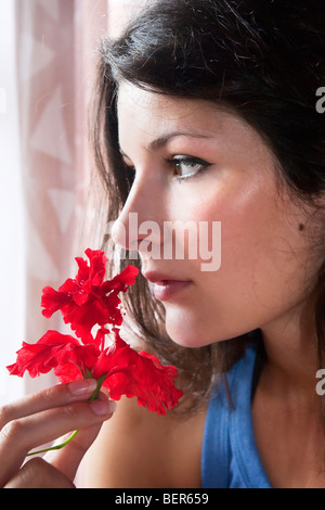 Giovane donna odorare un fiore Foto Stock