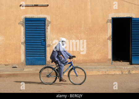 Il Tuareg uomo che indossa tagelmust equitazione Bicicletta in via della città Agadez, Niger, Africa occidentale Foto Stock