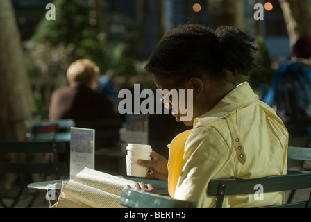 Un visitatore a Bryant Park di New York legge Foto Stock