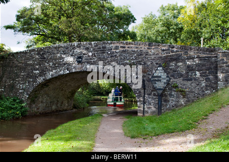 Canal Boat vela sotto il vecchio ponte in pietra 134 sulla Monmouth e Brecon Canal prese a Llangynidr metà del Galles a fine giornata