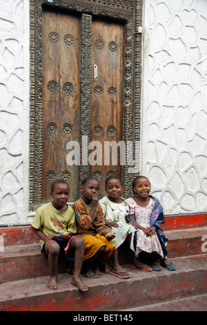 Quattro bambini seduti sulle scale nella vecchia medina di Stone Town / Stonetown / Mji Mkongwe, Zanzibar, Tanzania Africa orientale Foto Stock