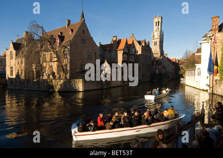 Belfry e turisti facendo una gita in barca sui famosi canali di Bruges, Fiandre Occidentali, Belgio Foto Stock