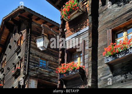 Tradizionale in legno Svizzera Case / Chalet decorati con gerani in estate nel villaggio alpino Grimentz, Vallese, Svizzera Foto Stock