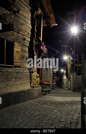 Street con i tradizionali in legno Svizzera Case / Chalet nel villaggio alpino Grimentz di notte, Valais / Wallis, Svizzera Foto Stock