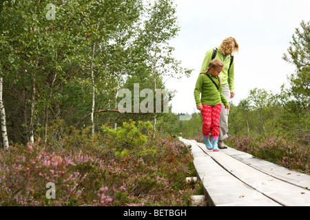 Madre e figlia camminando sul listone vie in foresta Foto Stock