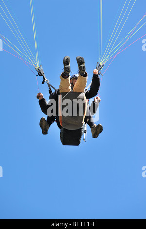 Parapendio in tandem, worm'occhio sul pilota e passeggero contro il cielo blu Foto Stock