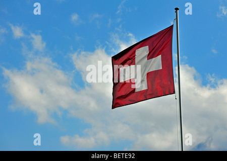 Bandiera svizzera sbattimenti nel vento contro il cielo nuvoloso, Svizzera Foto Stock